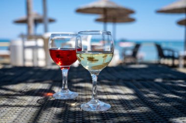 Soğuk gül ve beyaz şarap içmek güneşli kumlu sahildeki bar, arka planda mavi deniz suyu, yaz tatili