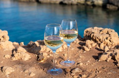 Kıbrıs 'taki Protaras turistik kasabası yakınlarındaki mavi deniz koyunda iki bardak beyaz şarap servis ediliyor.