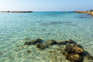 Kıbrıs Rum Kesimi 'nin Ayia Napa kentindeki beyaz kumlu Nissi plajında Akdeniz' in berrak mavi suyu