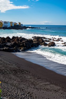 Kara kumlu sahil Playa Jardin 'i ve kışın Puerto de la Cruz, Tenerife, Kanarya Adaları' ndaki siyah lav kayalarını izleyin.