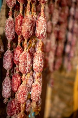 Parma, Emilia Romagna, İtalya 'daki kasapta asılı duran ev yapımı kurutulmuş salam sosisleri, et yemekleri arka planı.