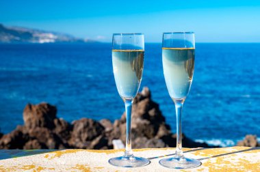Yeni yıl kutlamalarında iki kadeh şampanya ya da İspanyol kavası köpüklü şarap ve Atlantik 'in mavi suları, Kanarya adaları, kış turistleri
