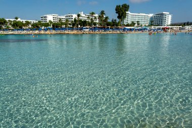 Kıbrıs Rum Kesimi 'nin Ayia Napa kentindeki beyaz kumlu Nissi plajında Akdeniz' in berrak mavi suyu