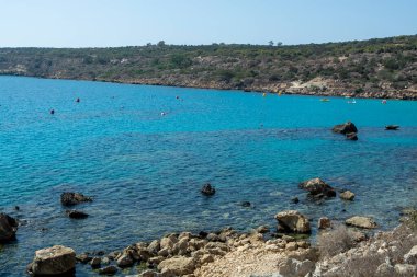 Akdeniz 'in berrak mavi suyu ve Kıbrıs Rum Kesimi' nin Protaras yakınlarındaki kumlu Konnos plajında sarı kayalar