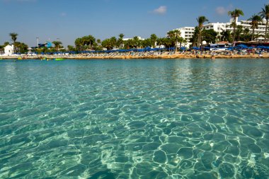 Kıbrıs Rum Kesimi 'nin Ayia Napa kentindeki beyaz kumlu Nissi plajında Akdeniz' in berrak mavi suyu