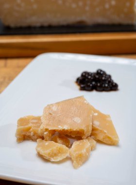 Parma 'dan 72 aylık İtalyan parmegiano-reggiano parmesan peyniri tadı son derece tahıllı ve parçalanmış bir yapısı ve siyah balzamik sirke incileri ile yoğun bir tadı var. Modena' dan DOP, yakın plan.