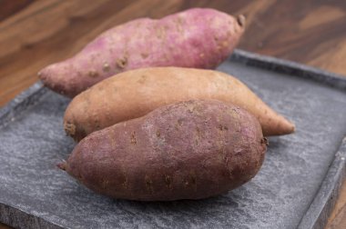 Renkli kök sebzeler pembe, mor ve turuncu organik tatlı patatesler yakın çekim