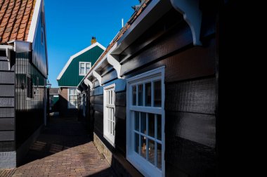 Hollanda 'nın küçük Marken kasabasında güneşli bir bahar gününde eski Hollanda, Hollanda' da bulunan ahşap evlerle yürüyorum.