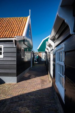 Hollanda 'nın küçük Marken kasabasında güneşli bir bahar gününde eski Hollanda, Hollanda' da bulunan ahşap evlerle yürüyorum.
