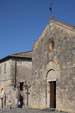 İtalya 'nın Toskana kentindeki Monteriggione tepesindeki ortaçağ kale kasabasındaki eski kasaba duvarlarının içindeki evler.