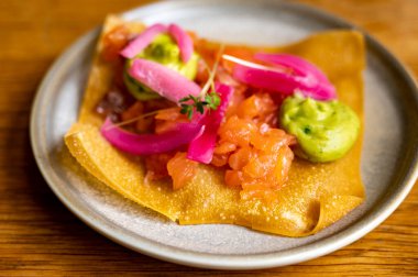 Meksika yemeği, kızarmış mısır tortilla füme somon, guacamole sosu ve pembe soğan turşusu.