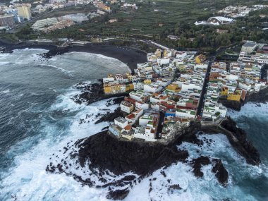 Puerto de la Cruz, Tenerife, Kanarya Adaları yakınlarındaki küçük balıkçı köyünde renkli evlerin ve siyah lav kayalarının hava manzarası.