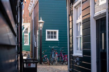 Hollanda 'nın küçük Marken kasabasında güneşli bir bahar gününde eski Hollanda, Hollanda' da bulunan ahşap evlerle yürüyorum.