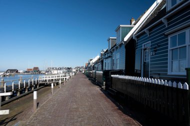 Hollanda 'nın küçük Marken kasabasında güneşli bir bahar gününde eski Hollanda, Hollanda' da bulunan ahşap evlerle yürüyorum.