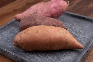 Renkli kök sebzeler pembe, mor ve turuncu organik tatlı patatesler yakın çekim