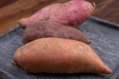 Renkli kök sebzeler pembe, mor ve turuncu organik tatlı patatesler yakın çekim