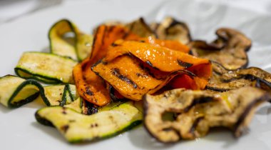 İtalyan mutfağı, rengarenk sebzeler kabak, patlıcan, beyaz tabakta baharatlı balkabağı.