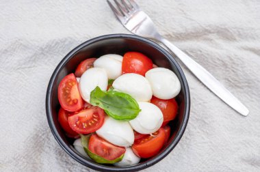 İtalyan yemeği, kırmızı kiraz domatesli kapuçin salatası, beyaz mozzarella peyniri ve yeşil fesleğen yaprağı.