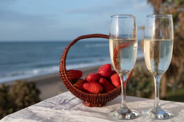 İspanyol bardakları taze çilekli köpüklü şarap mavi deniz ve kumlu plaj manzaralı Costa del Sol yaz tatili merkezi Endülüs, İspanya