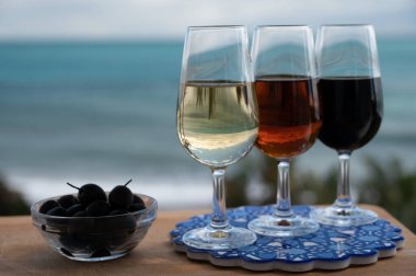 Tasting of Spanish sweet and dry fortified Vino de Jerez sherry wine and green olives with view on blue sea and beach near El Puerto de Santa Maria, Andalusia, Spain clipart