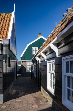 Hollanda 'nın küçük Marken kasabasında güneşli bir bahar gününde eski Hollanda, Hollanda' da bulunan ahşap evlerle yürüyorum.