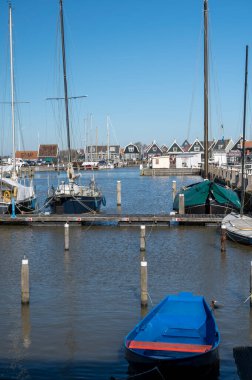 Hollanda 'nın küçük Marken kasabasında güneşli bir bahar gününde eski Hollanda, Hollanda' da bulunan ahşap evlerle yürüyorum.