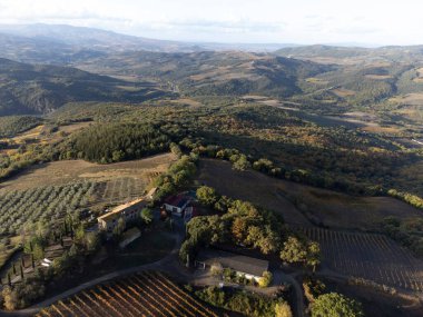 Bagno Vignoni, Tuscany, İtalya yakınlarındaki tepelere bakın. Selvi ağaçları, üzüm bağları, ormanlar ve bulutlu sonbaharda sürülen tarlalarla Toskana manzarası.