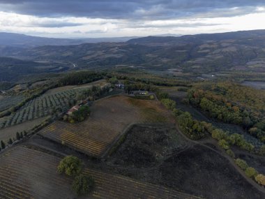 Bagno Vignoni, Tuscany, İtalya yakınlarındaki tepelere bakın. Selvi ağaçları, üzüm bağları, ormanlar ve bulutlu sonbaharda sürülen tarlalarla Toskana manzarası.