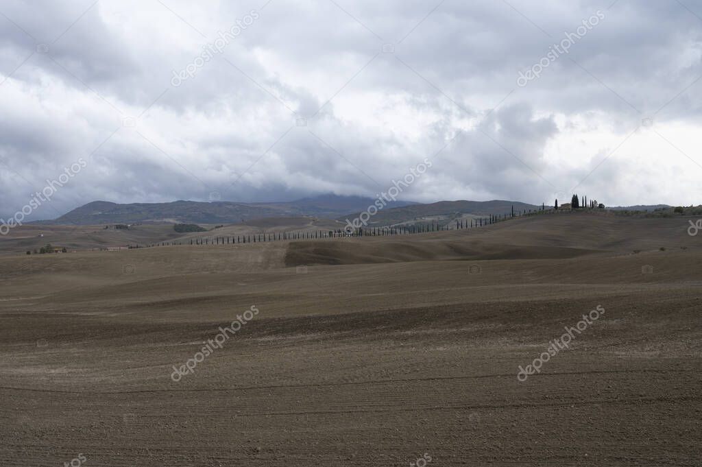 View on hills of Tuscany, Italy. Tuscan landscape with ploughed fields in cloudy autumn.
