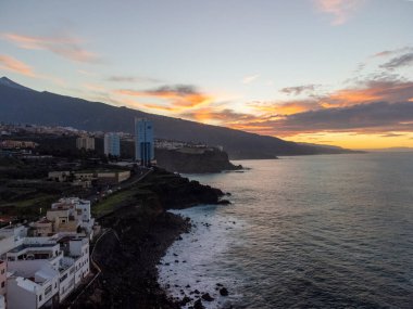 Günbatımında Puerto de la Cruz, Tenerife, Kanarya adaları yakınlarındaki küçük balıkçı köyündeki renkli evler ve siyah lav kayaları.
