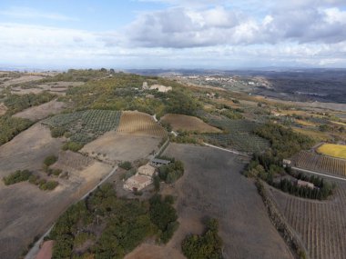 Bagno Vignoni, Tuscany, İtalya yakınlarındaki tepelerde hava panoramik manzarası. Selvi ağaçları, üzüm bağları, ormanlar ve bulutlu sonbaharda sürülen tarlalarla Toskana manzarası.