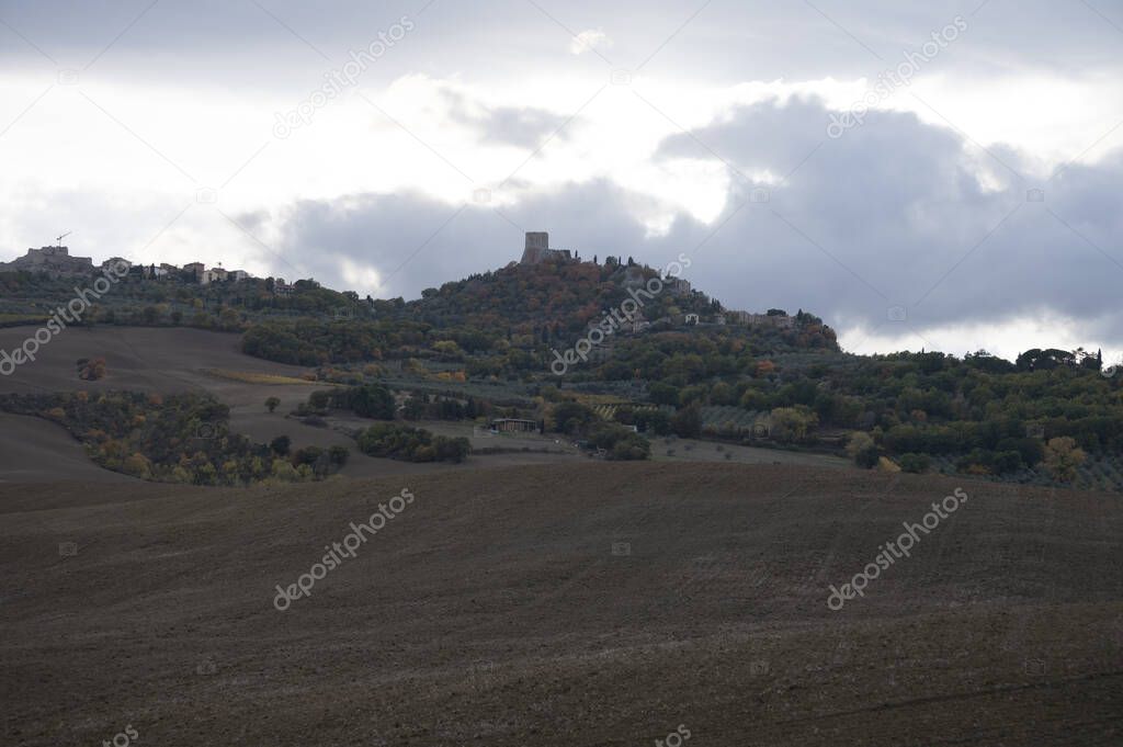 View on hills of Tuscany, Italy. Tuscan landscape with cypress trees and ploughed fields in autumn on sunset