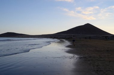 Tenerife Adası, İspanya 'nın güneyindeki El Medano' da kumlu sahilde gün batımında dinleniyorum.