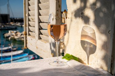 Açık terasta sunulan Rose Provencal şarabı Cassis, Provence, Fransa 'daki eski balıkçıların limanında renkli teknelerle servis ediliyor.