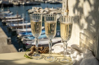Üç bardak Fransız şampanyası köpüklü şarap ve renkli balıkçı teknelerinin manzarası Cassis, Provence, Fransa 'daki eski limanda, yaz partisinde