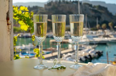 Üç bardak Fransız şampanyası köpüklü şarap ve renkli balıkçı teknelerinin manzarası Cassis, Provence, Fransa 'daki eski limanda, yaz partisinde