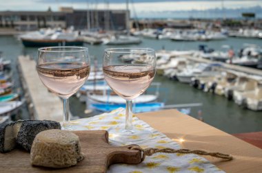 Açık terasta sunulan Rose Provencal şarabı Cassis, Provence, Fransa 'da renkli tekneleri olan eski balıkçıların limanına bakıyor.