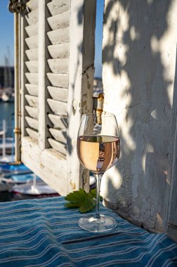 Açık terasta sunulan Rose Provencal şarabı Cassis, Provence, Fransa 'daki eski balıkçıların limanında renkli teknelerle servis ediliyor.