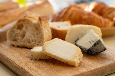 Provence 'de güneşli bir sabah, taze kruvasan, baquett ekmeği, crottin keçi peyniri ve Cassis, Provence, Fransa limanındaki balıkçı tekneleri manzaralı bir kahvaltı.