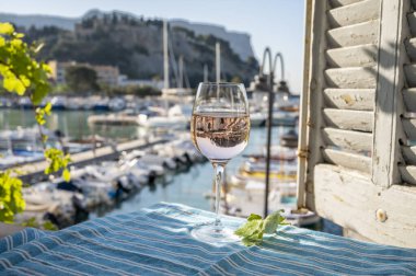 Açık terasta sunulan Rose Provencal şarabı Cassis, Provence, Fransa 'daki eski balıkçıların limanında renkli teknelerle servis ediliyor.