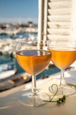 Soğuk gül Provencal şarabı bardaklarla sunuluyor. Açık terasta sunuluyor. Eski balıkçıların limanında, Cassis, Provence, Fransa 'da renkli tekneleri var.