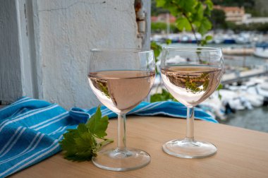 Açık terasta sunulan Rose Provencal şarabı Cassis, Provence, Fransa 'da renkli tekneleri olan eski balıkçıların limanına bakıyor.