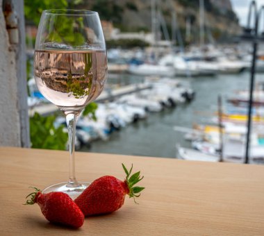 Açık terasta sunulan Rose Provencal şarabı Cassis, Provence, Fransa 'daki eski balıkçıların limanında renkli teknelerle servis ediliyor.