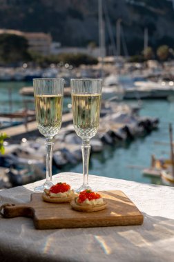 Ekşi krema ve tuzlu somon kırmızısı havyar ve Fransız şampanyası brut köpüklü şarap ile küçük krep çiftleri Cassis, Provence, Fransa 'nın limanındaki renkli teknelerde servis edilir.