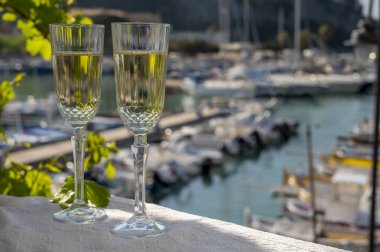 İki bardak Fransız şampanyası, köpüklü şarap ve renkli balıkçı teknesiyle Cassis, Provence, Fransa 'daki eski limanda öğle yemeği.