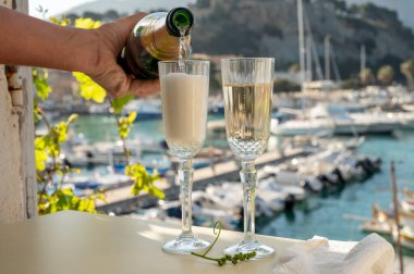 İki bardak Fransız şampanyası, köpüklü şarap ve renkli balıkçıların Cassis, Provence, Fransa 'da eski bir limandaki teknelerine manzarası, Provence' de yaz tatili.