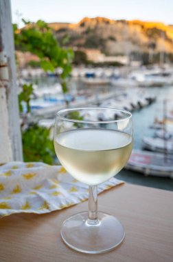 Cassis şarap üretim bölgesinden gelen soğuk beyaz şarap, Fransa, Provence, Cassis 'te renkli tekneleri olan eski balıkçıların limanına bakan terastaki camlarda servis edilir.