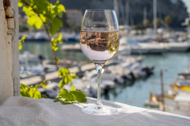 Açık terasta sunulan Rose Provencal şarabı Cassis, Provence, Fransa 'daki eski balıkçıların limanında renkli teknelerle servis ediliyor.