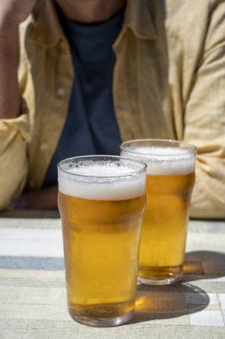 Güneşli yaz gününde Fransız açık hava kafesinde iki bardak taze soğuk bira içen adamlar.