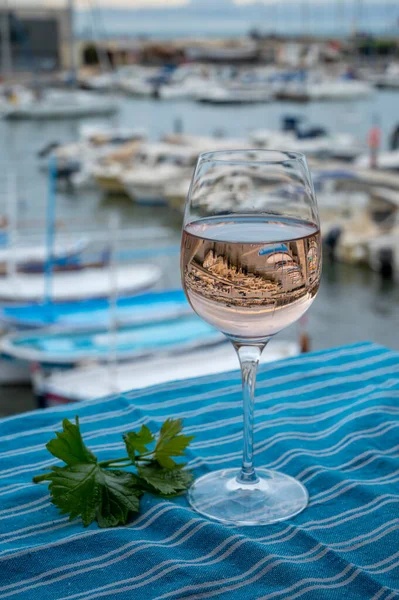 Açık terasta sunulan Rose Provencal şarabı Cassis, Provence, Fransa 'daki eski balıkçıların limanında renkli teknelerle servis ediliyor.